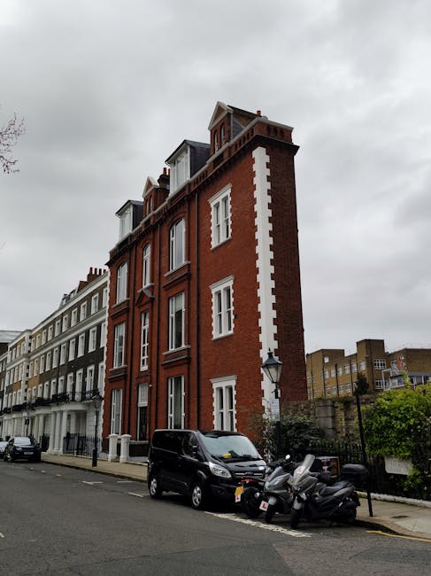 A multi-storey residential building in a traditional brick Victorian style, with red brick walls and white decorative stonework around the windows and along the edges. The building features several la