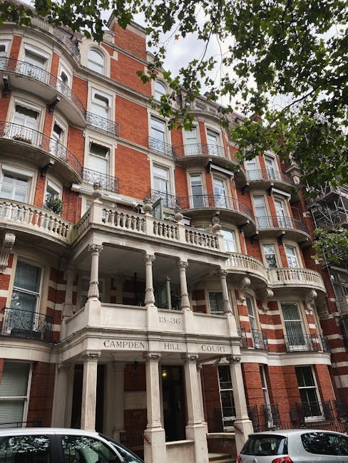 A multi-storey residential building in a traditional brick Victorian style, with red brick walls and white decorative stonework around the windows and along the edges. The building features several la